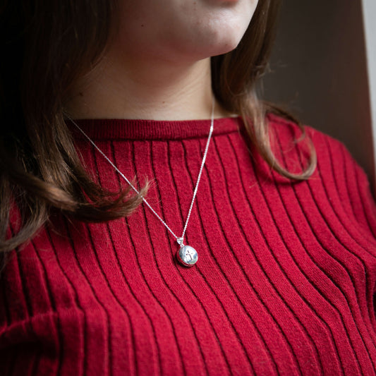 model in red top wearing delicate round locket