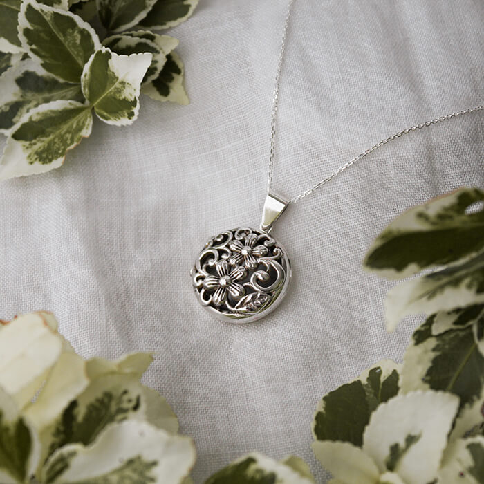 Silver Locket Necklace on a linen background with foliage