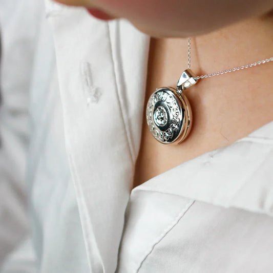 Large round silver locket worn by a young model