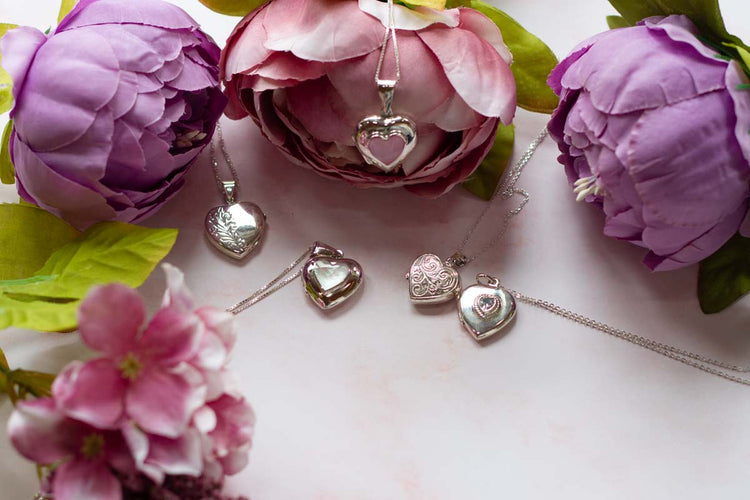 five heart locket necklaces arranged around some flowers