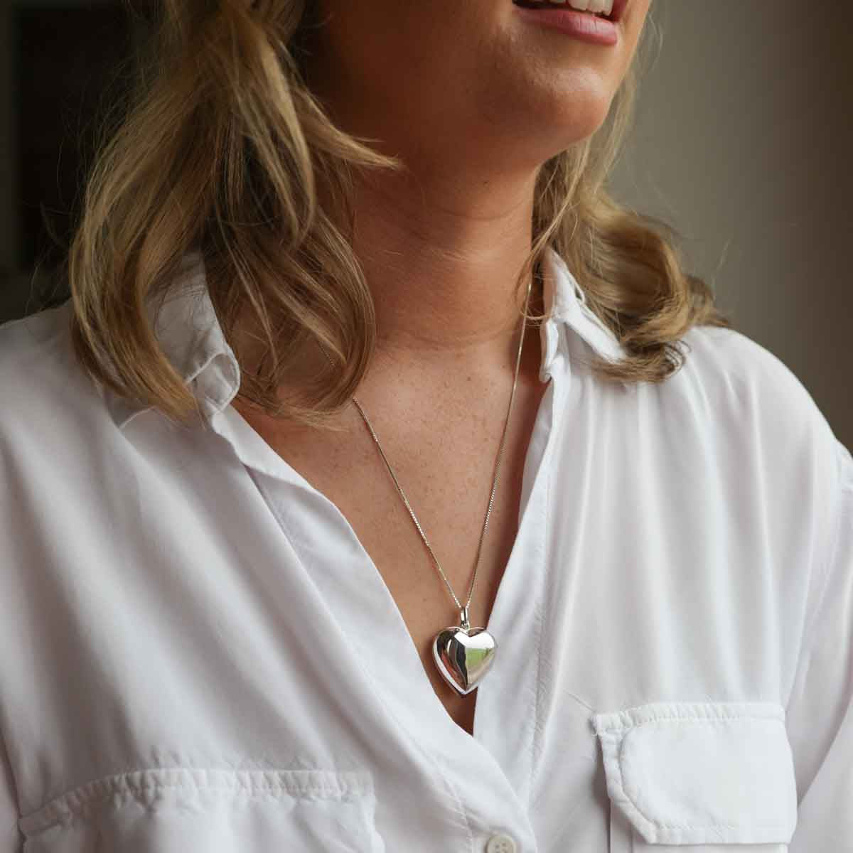Model in white shirt with large heart shaped locket