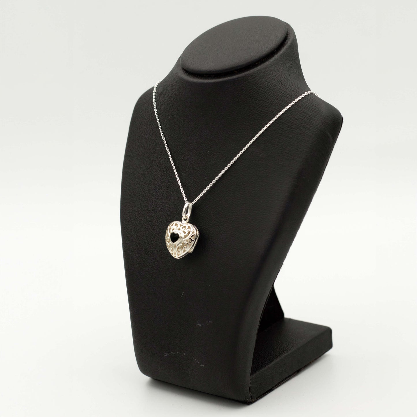 silver locket necklace photographed on a black bust