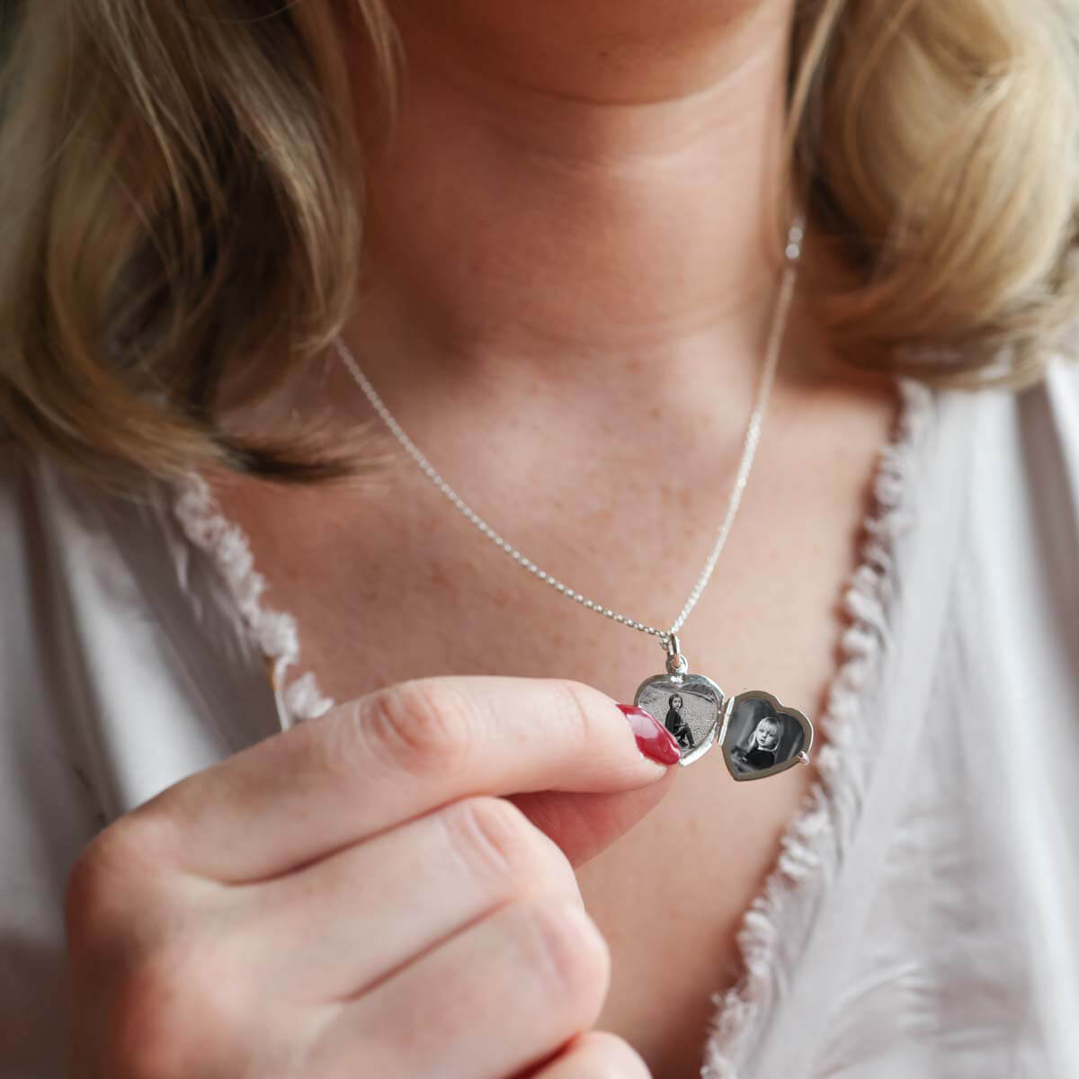 Model holding open heart locket necklace