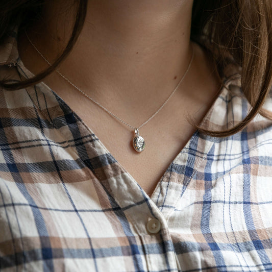 Model wearing a small oval locket with CZ embellishment