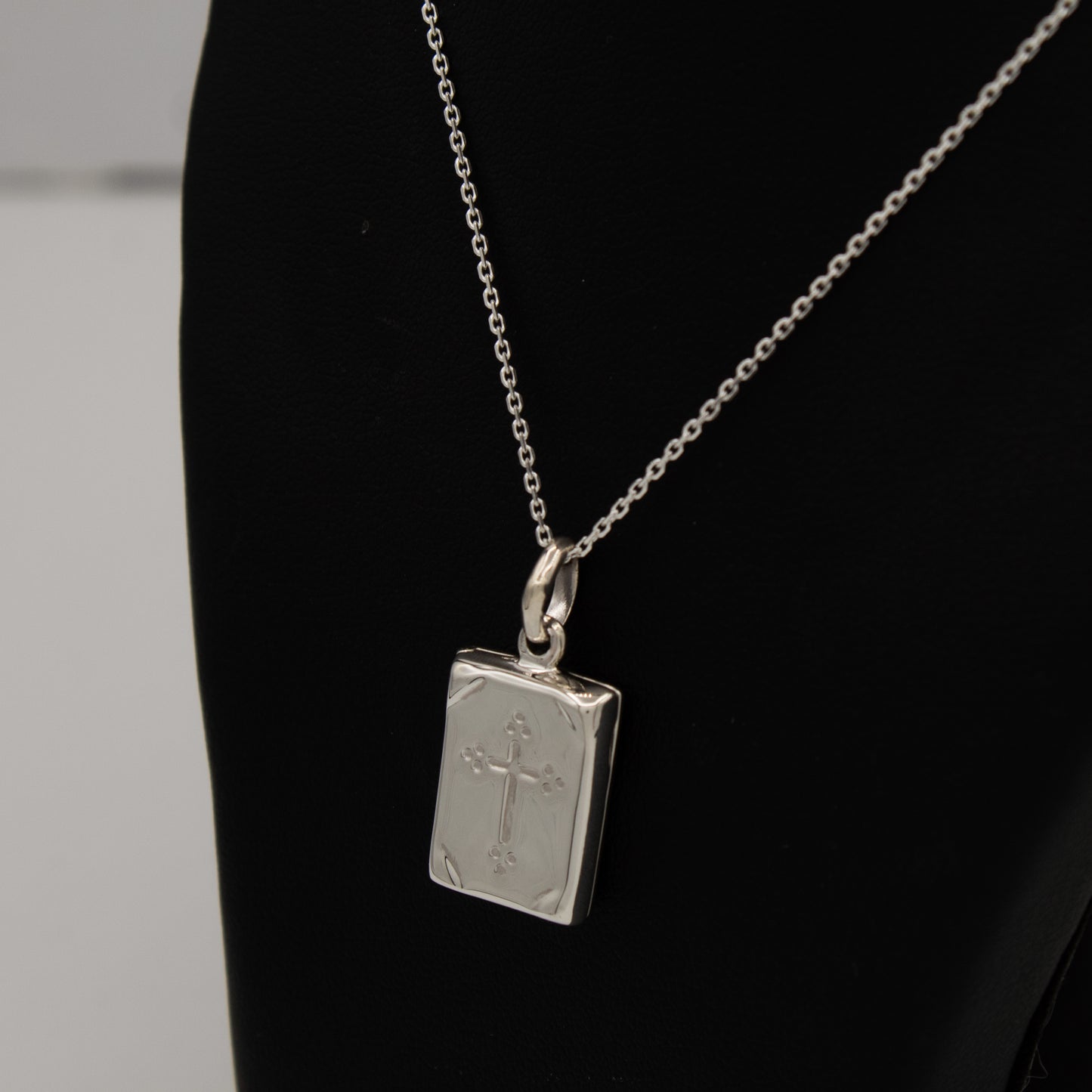 Holy Communion Locket displayed with a silver chain on a blackbust