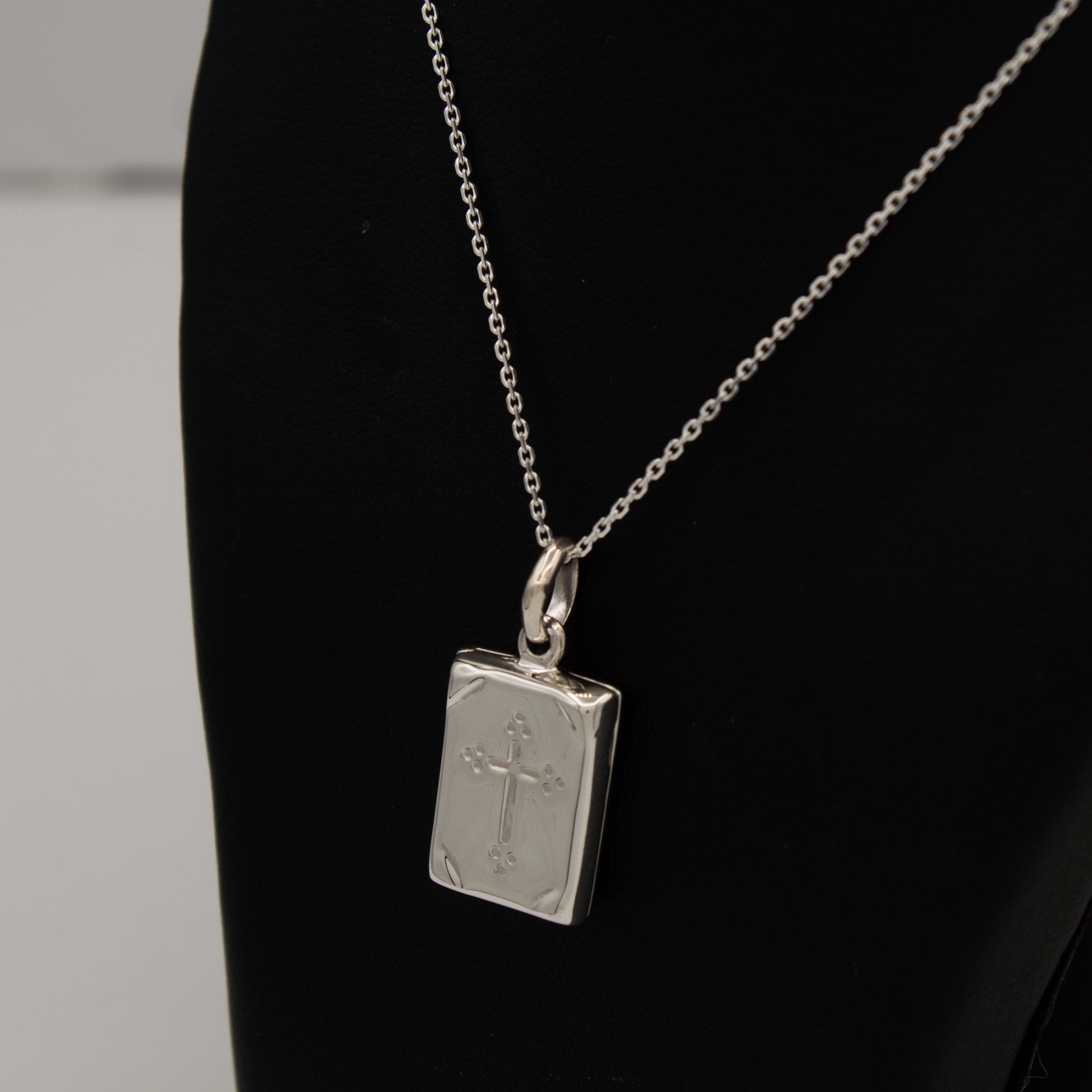 Holy Communion Locket displayed with a silver chain on a blackbust