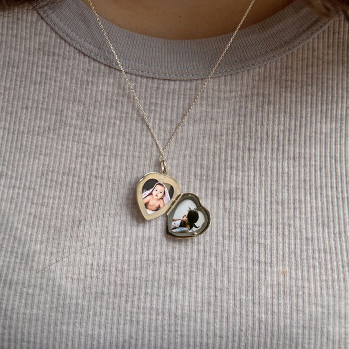 Model wearing open sterling silver locket revealing two photos. 