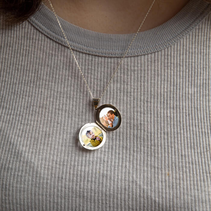 model showing large silver locket open with photos