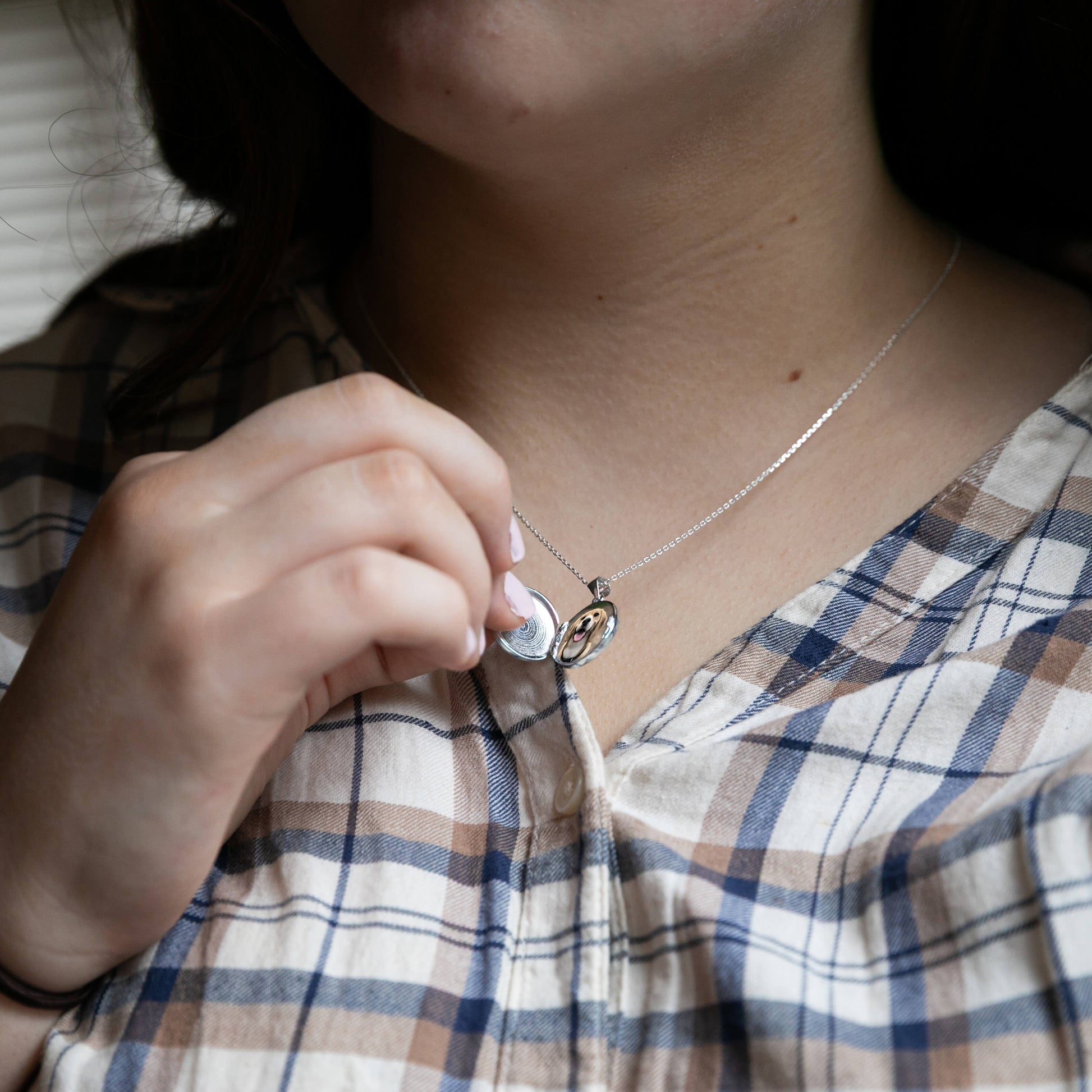 Model holding round silver locket openm