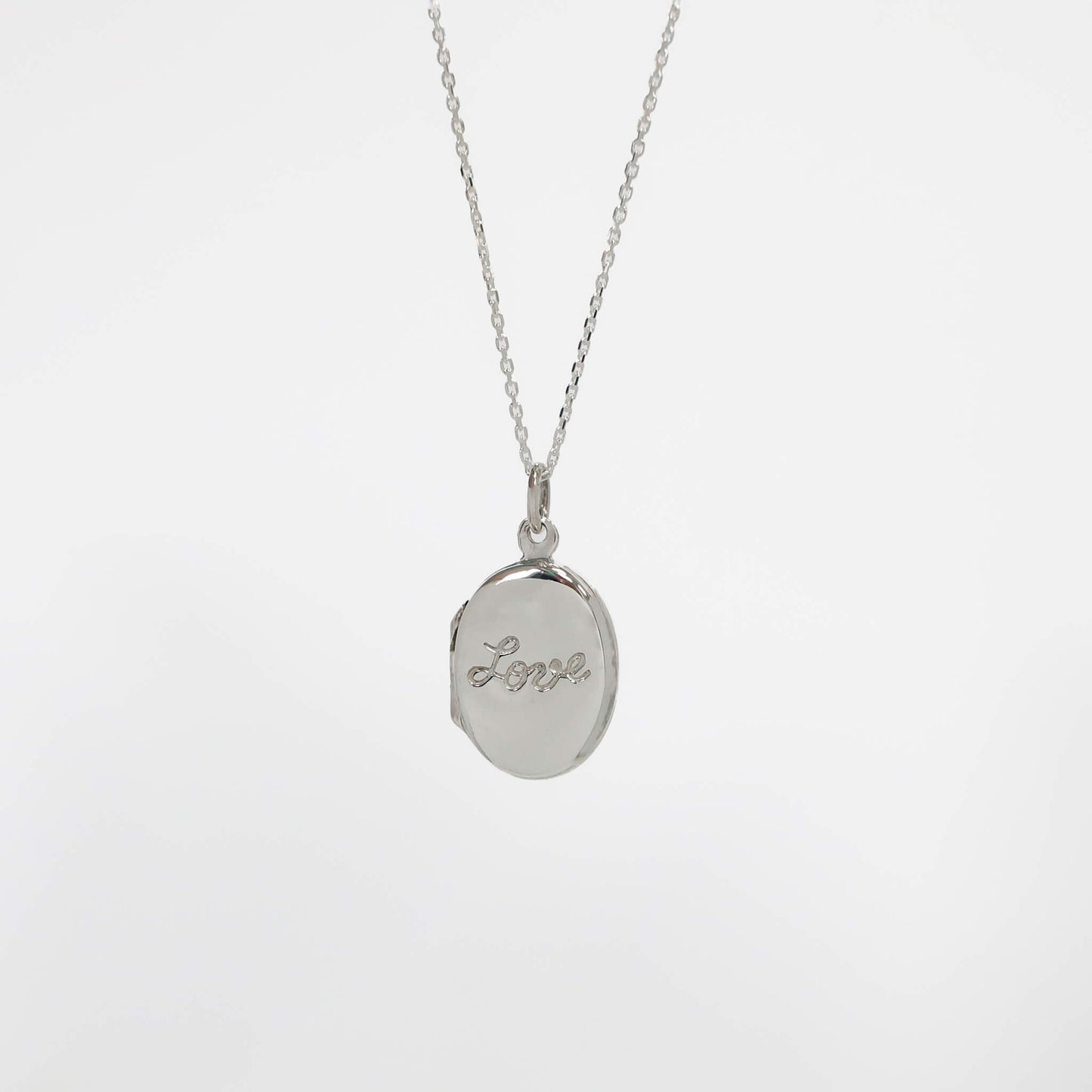 Silver photo locket necklace with a locket pendant engraved with 'love' on a light gray background