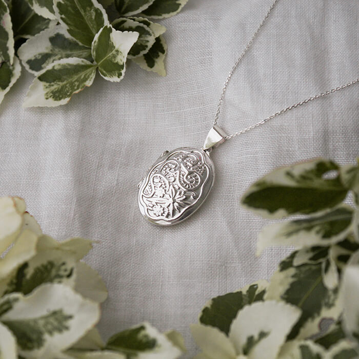 large silver oval locket on a white linen background