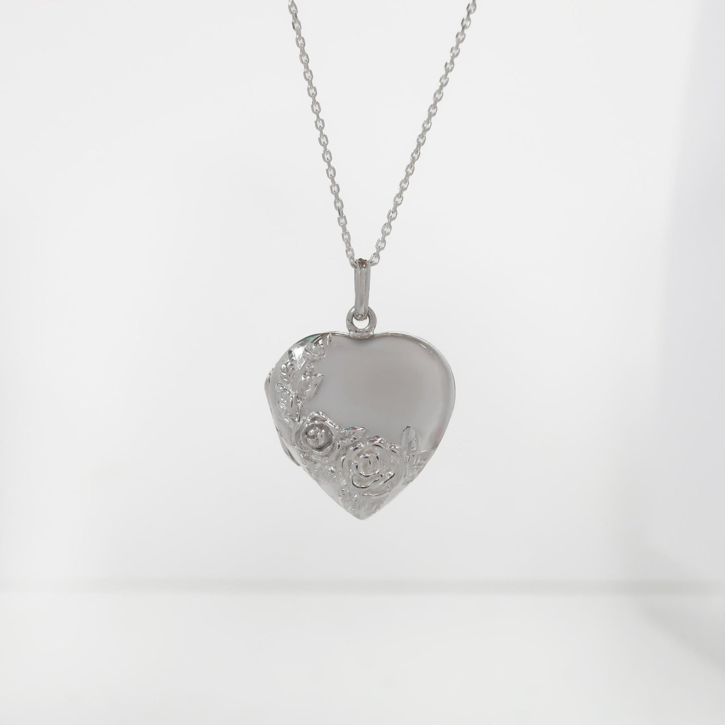 Silver heart-shaped pendant on a chain against a white background
