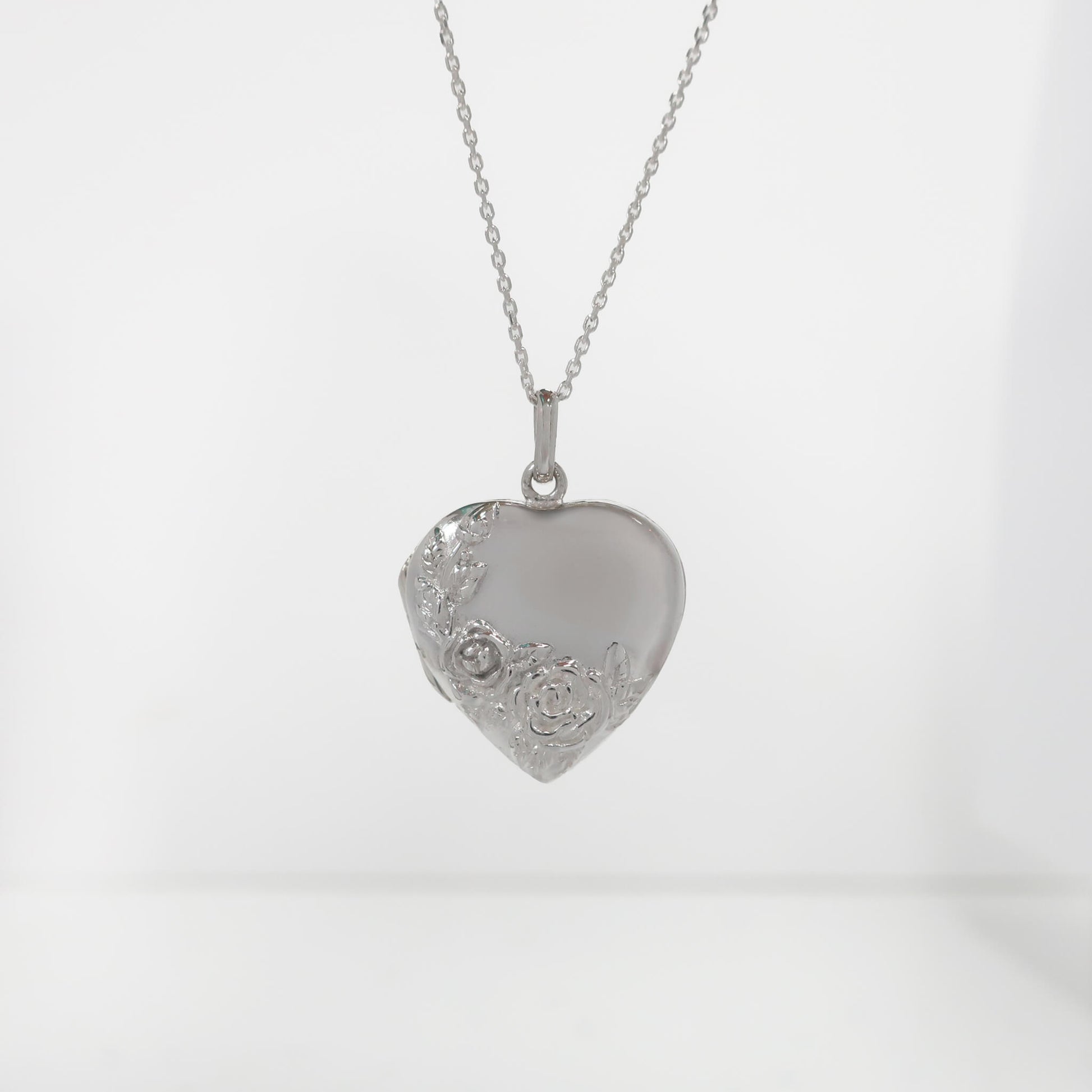 Silver heart-shaped pendant on a chain against a white background