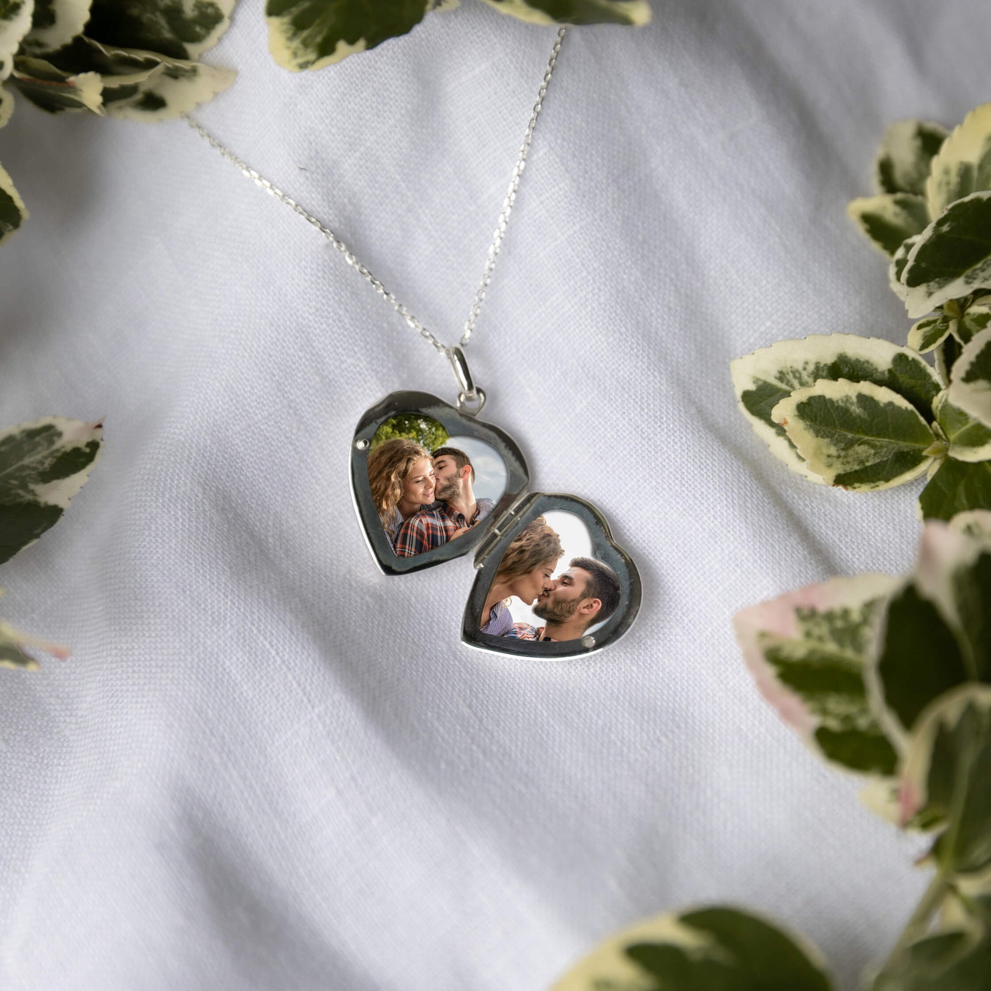 Heart-shaped locket with photos on a white fabric background