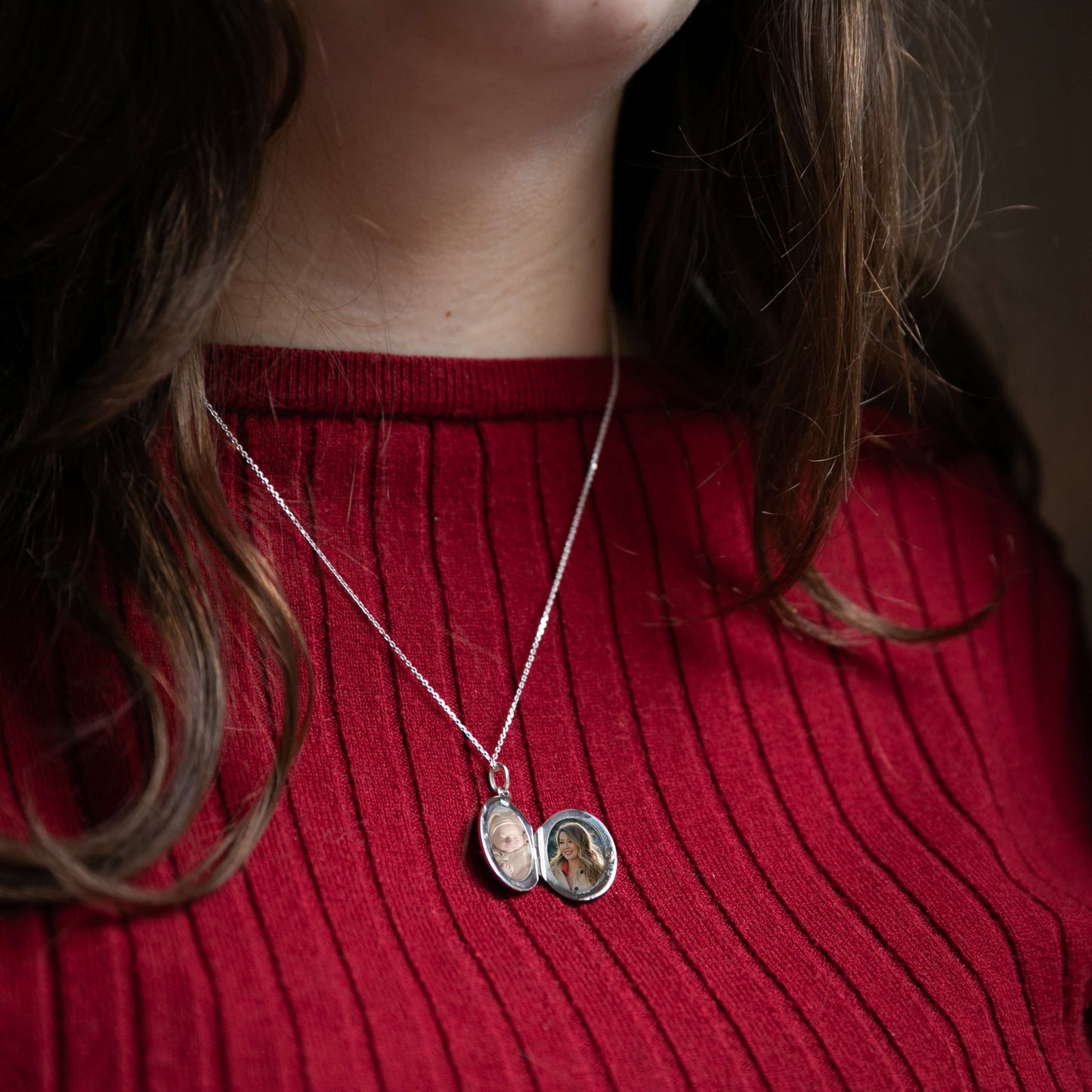 Model wearing red with oval locket open revealing photos