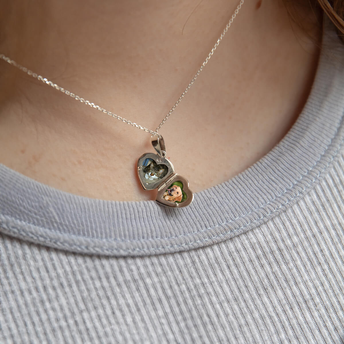 model wearing tiny kids locket opened to show photos inside