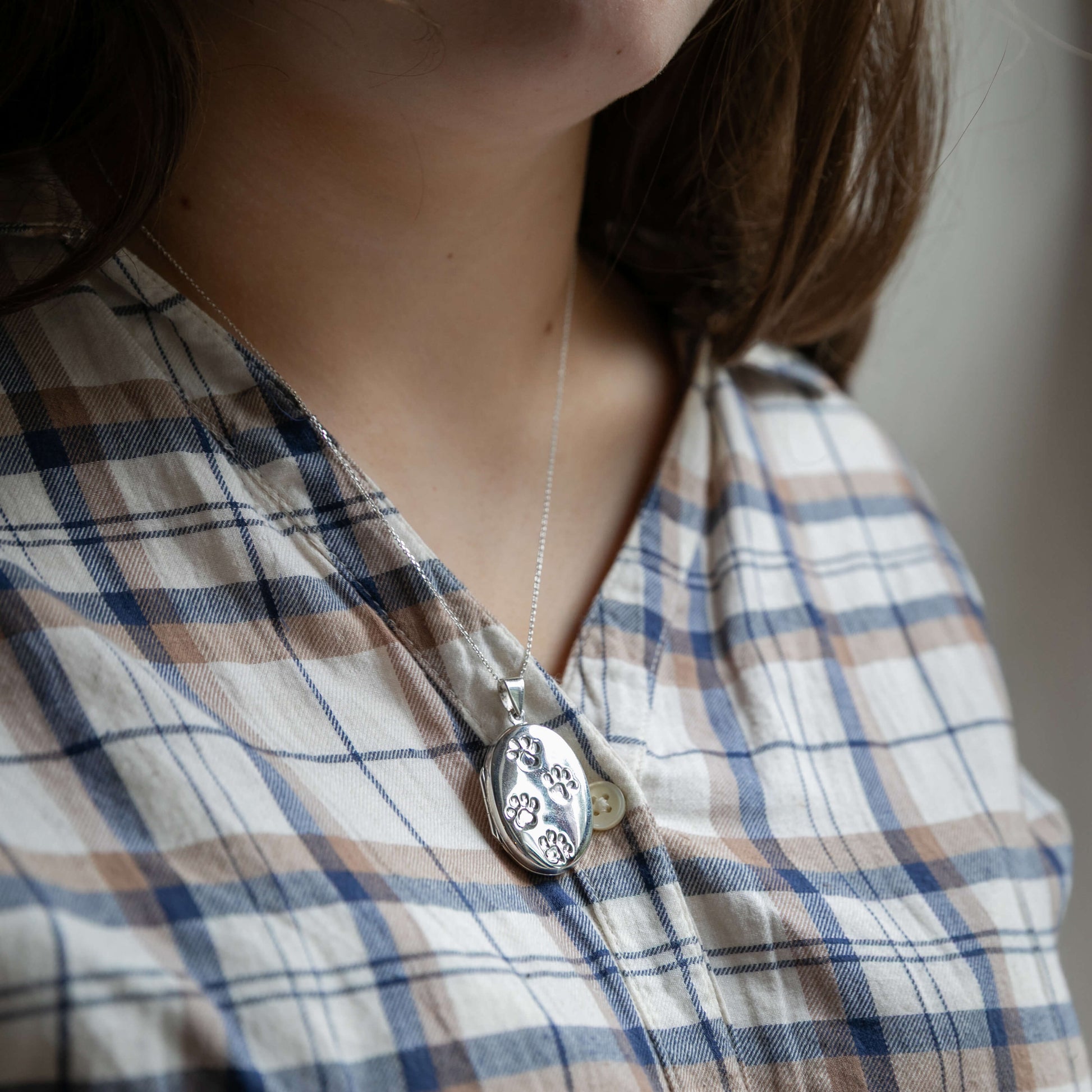 model wearing large oval locket with paw prints