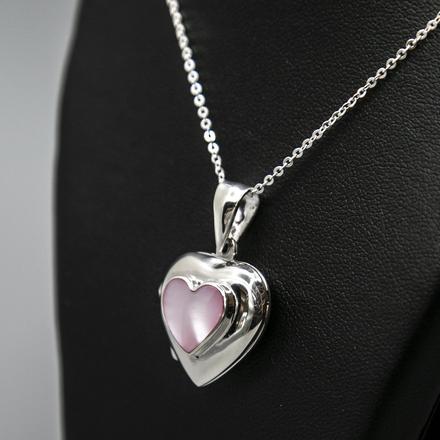 Pink heart locket with mother of pearl inset with a silver Italian chain displayed on a black bust.