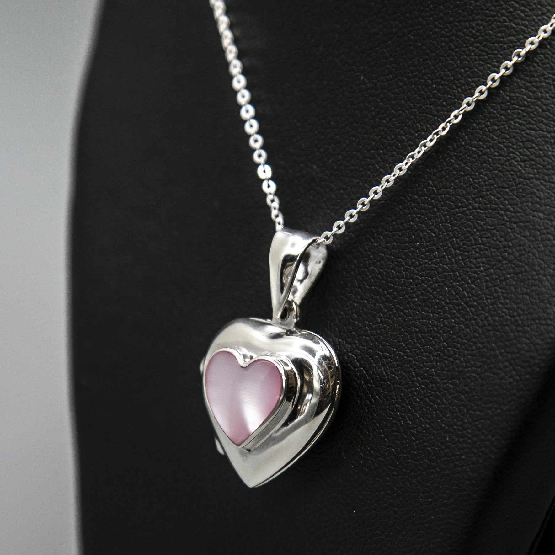 Pink heart locket with mother of pearl inset with a silver Italian chain displayed on a black bust.