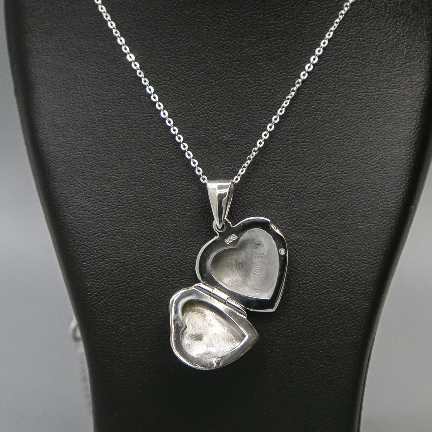 Silver heart-shaped photo locket necklace with pink mother of pearl inset with a silver chain displayed on a black bust. Photo locket necklace is open showing where photos are inserted.