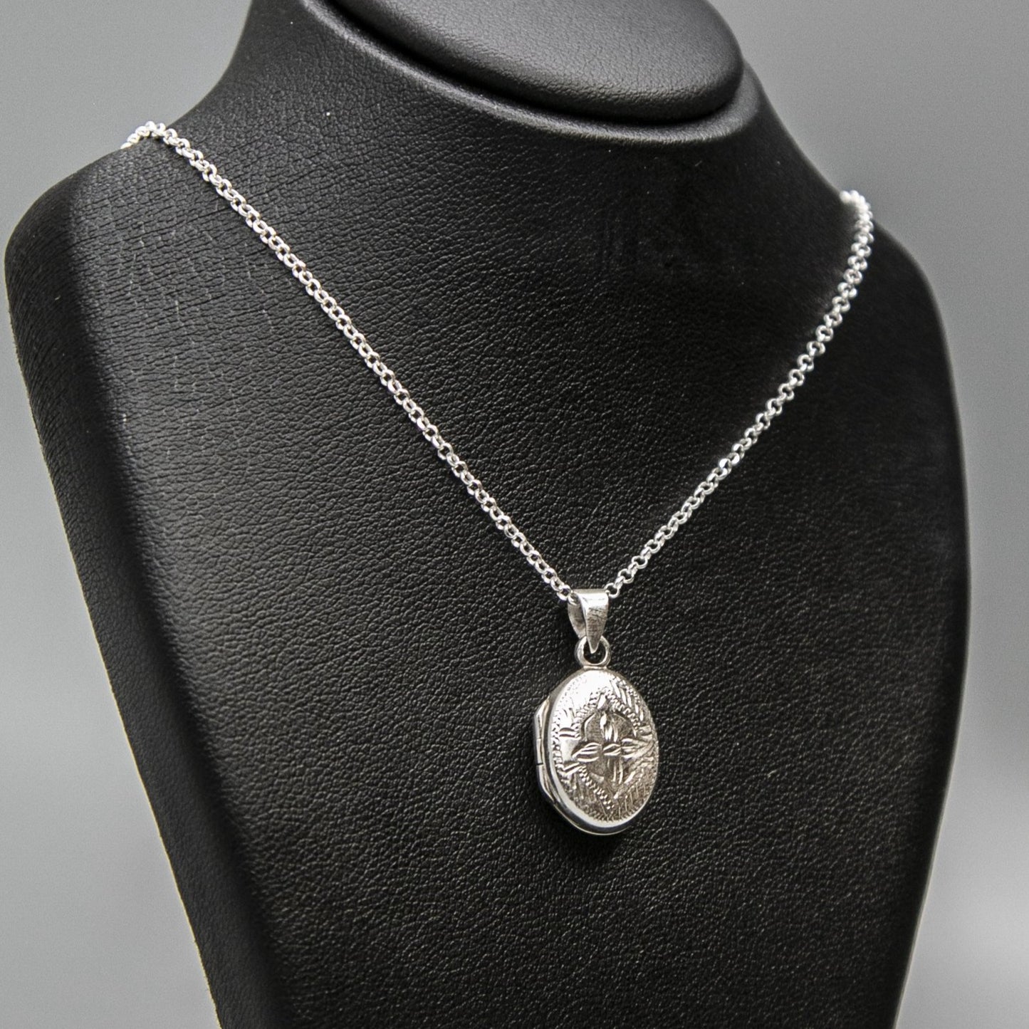 Embellished silver photo locket necklace with lily motif on Italian silver chain displayed on black bust.