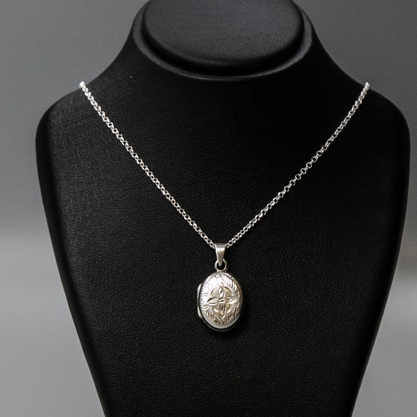Oval shaped embellished silver photo locket necklace with lily motif on Italian silver chain displayed on black bust.