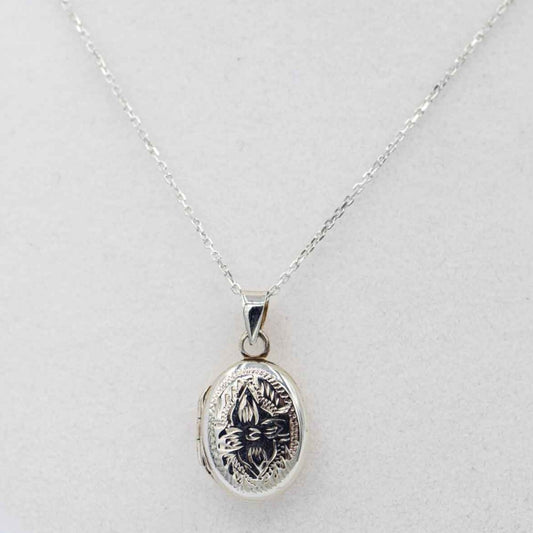 dainty ornate oval silver locket on white bust.